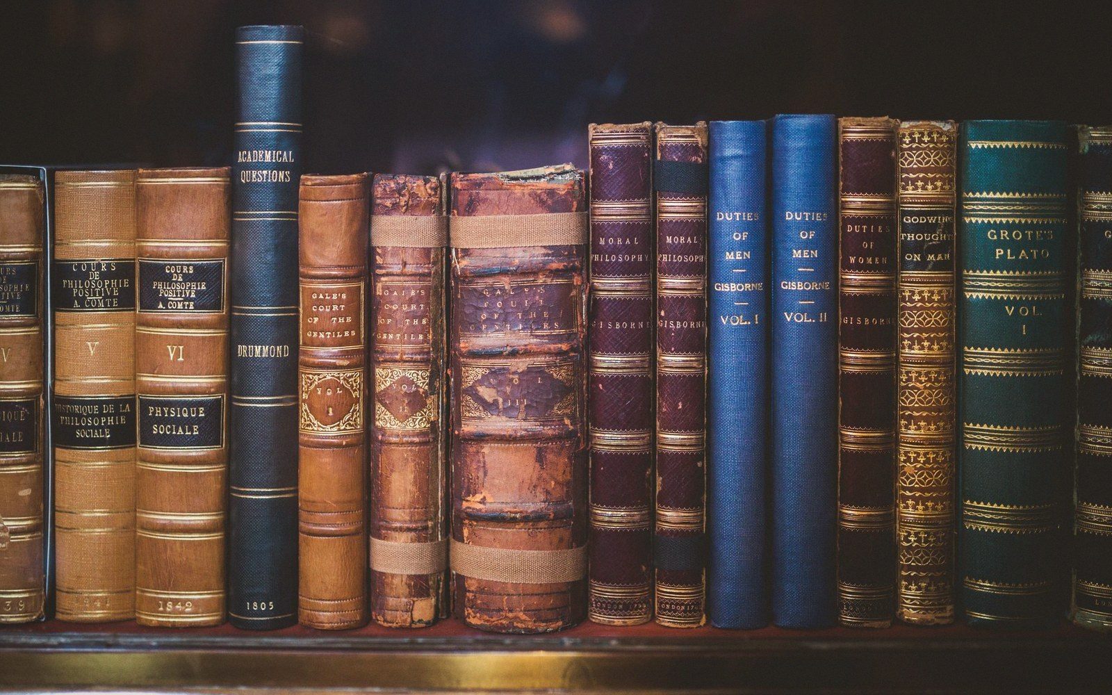 A locked glass-fronted rare-book case with rows of leather and vellum-bound volumes, empty of people
